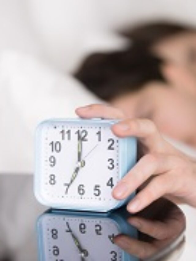 Couple being woken by alarm, man turning off ringing clock